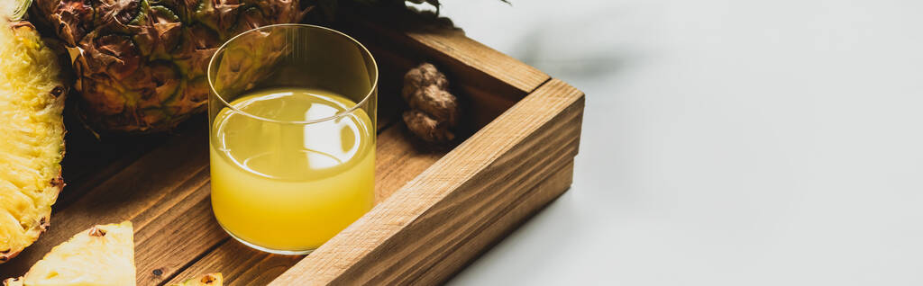 świeży sok ananasowy i pokroić pyszne owoce na drewnianej tacy na białym tle, orientacja panoramiczna - Zdjęcie, obraz