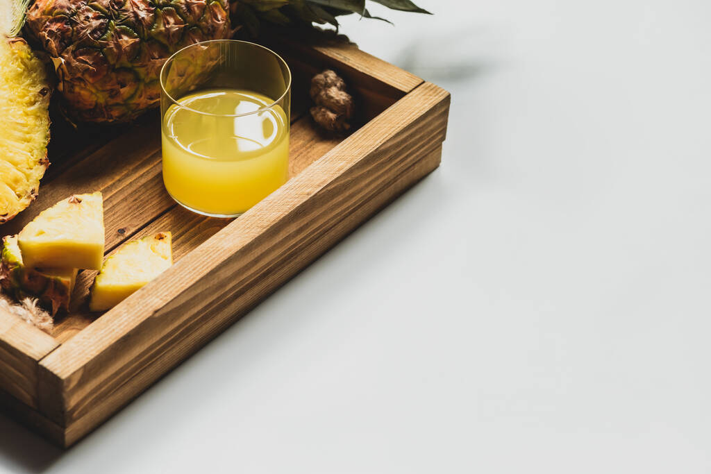 suco de abacaxi fresco e cortar frutas deliciosas na bandeja de madeira no fundo branco
 - Foto, Imagem