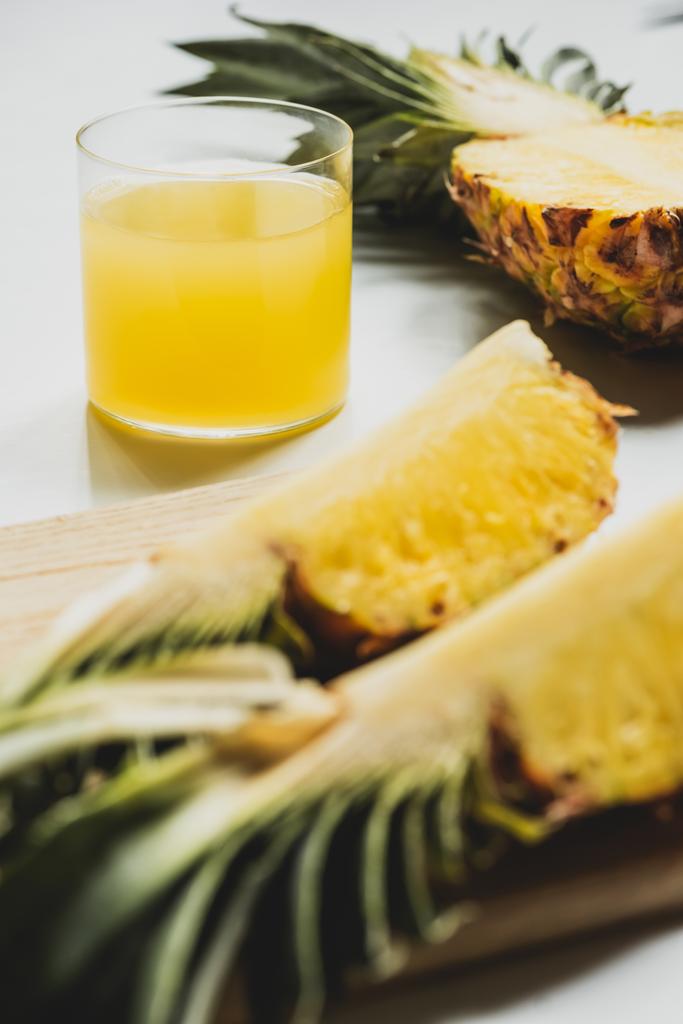 szelektív fókusz a friss ananászlé közel vágott finom gyümölcs vágódeszka fehér alapon - Fotó, kép