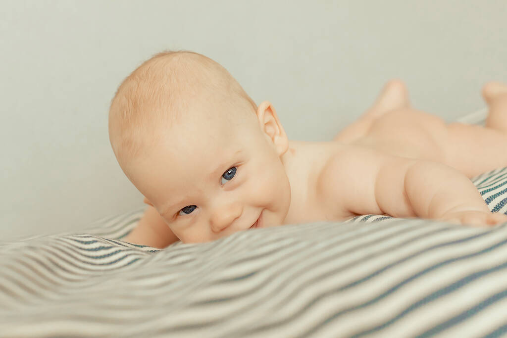Sevimli erkek bebek yüzüstü yatıp gülümsüyor.. - Fotoğraf, Görsel