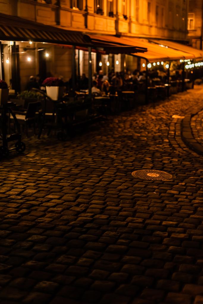 selective focus of paving stones on road near cafe with terrace  - Photo, Image