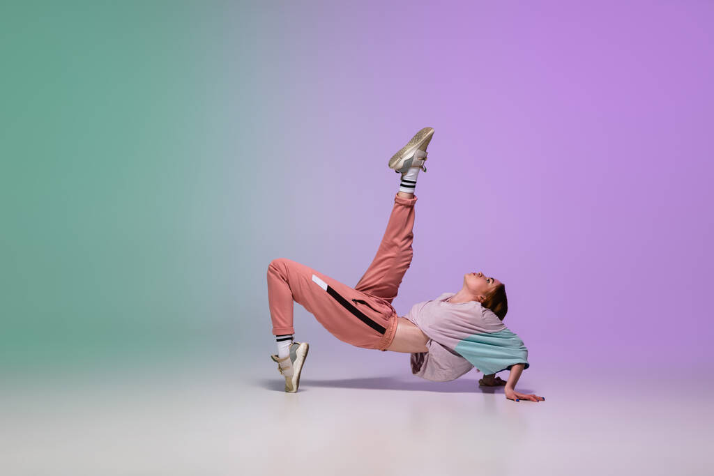 Dívka tanec hip-hop ve stylovém oblečení na gradient pozadí v tanečním sále v neonovém světle. - Fotografie, Obrázek