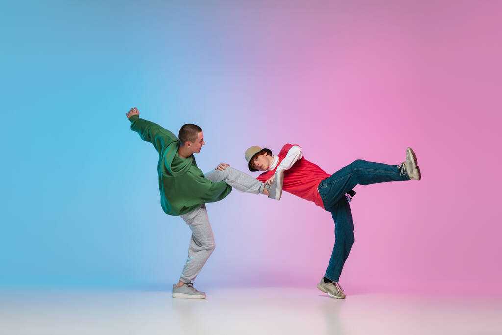 Fiúk táncoló hip-hop divatos ruhákat gradiens háttér táncterem neon fény. - Fotó, kép