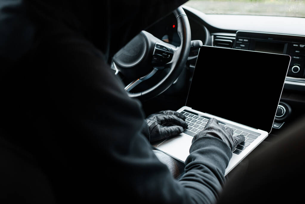Enfoque selectivo del ladrón en guantes de cuero usando computadora portátil en el coche
  - Foto, imagen
