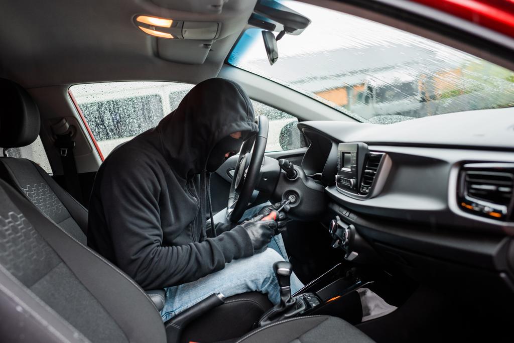 Arabada tornavida kullanarak kar maskesi ve deri eldivendeki hırsızlığın yan görüntüsü  - Fotoğraf, Görsel