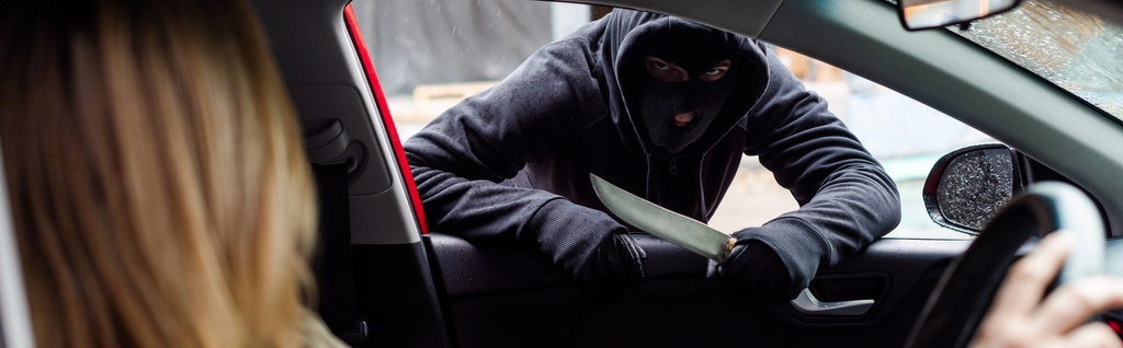 Foto panorámica de ladrón en pasamontañas sosteniendo cuchillo cerca de mujer en coche
  - Foto, imagen