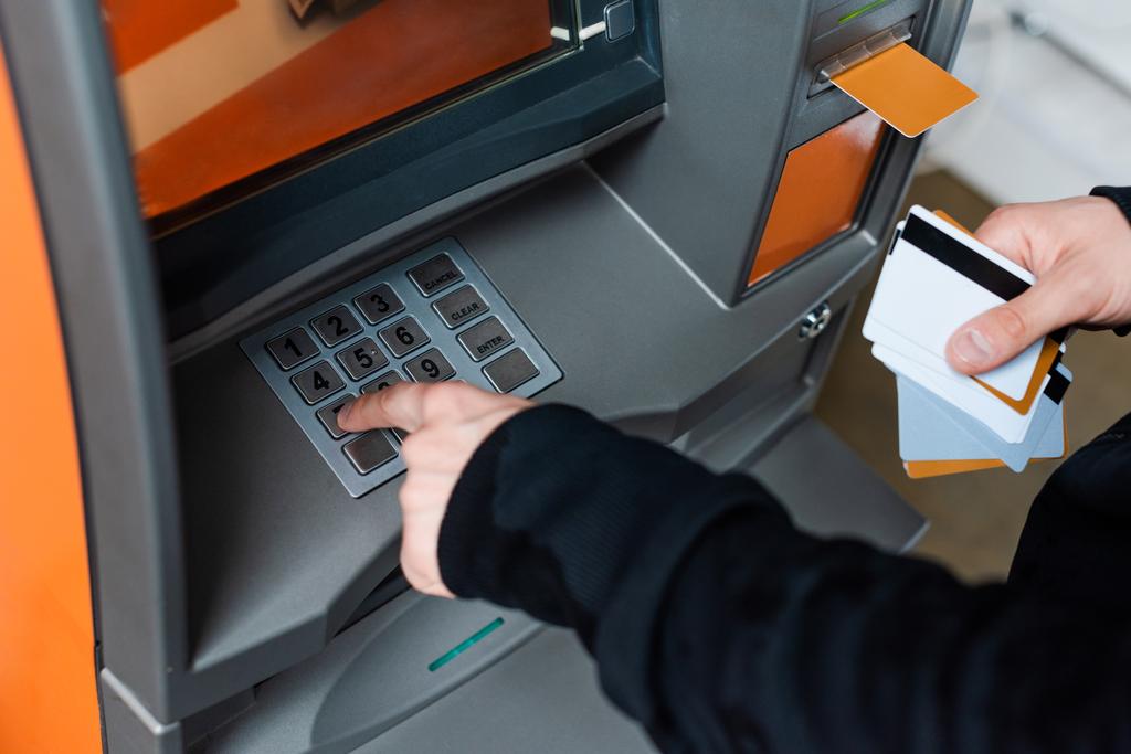 Oříznutý pohled na zloděje pomocí bankomatu při držení kreditních karet  - Fotografie, Obrázek