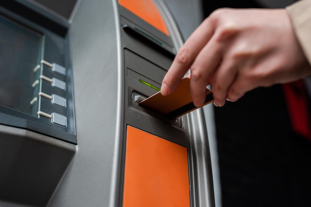 Обрезанный вид женщины, держащей кредитную карту во время использования банкомата
  - Фото, изображение