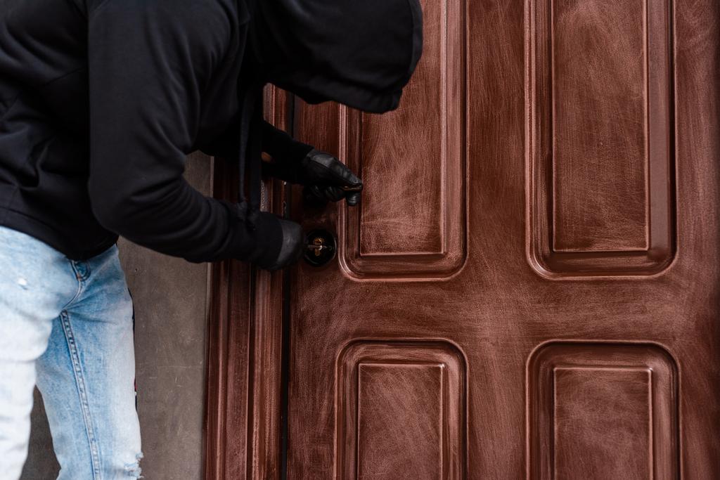 Kapı kilidini açarken tornavida kullanan ev hırsızının yan görünümü  - Fotoğraf, Görsel