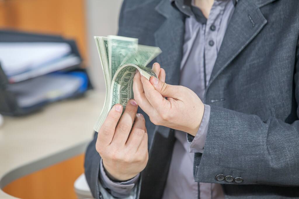 Un joven empresario trabajando desde su oficina y contando dinero en efectivo - Foto, imagen
