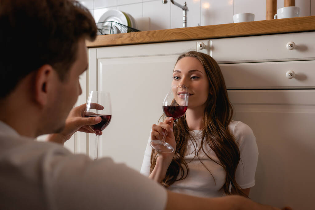 赤ワインのグラスを持って男を見て幸せな女性の選択的な焦点  - 写真・画像