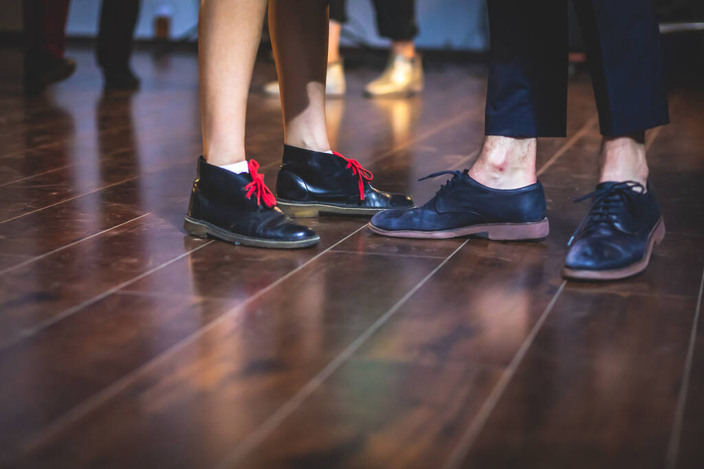 Tanzschuhe von jungen Paaren tanzen Retro-Jazz-Swing-Tänze auf dem Holzboden eines Gesellschaftslokals, Nahsicht auf Schuhe, weiblich und männlich, Tanzunterricht - Foto, Bild
