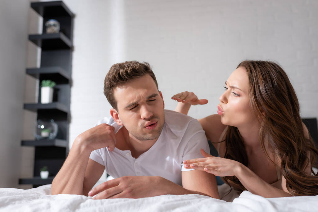 attraente donna gesturing e soffiando su fidanzato in camera da letto
  - Foto, immagini