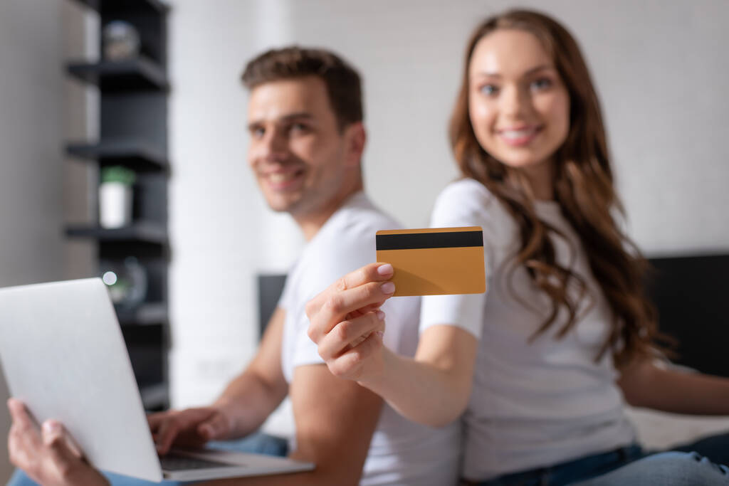 selektivní zaměření šťastný žena držící kreditní kartu v blízkosti muže a notebooku  - Fotografie, Obrázek