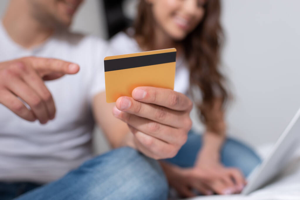 Ausgeschnittene Ansicht eines Mannes, der mit dem Finger auf Kreditkarte in der Nähe der Frau zeigt - Foto, Bild