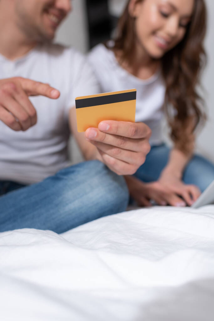 valikoiva painopiste mies sormella luottokortilla lähellä naista kotona  - Valokuva, kuva