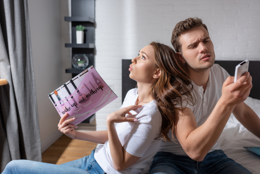 woman woman holding magazine while feeling hot near man with remote controller from air conditioner - Photo, Image