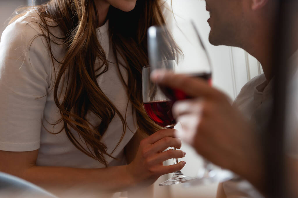 vista recortada de pareja sosteniendo vasos de vino tinto
  - Foto, imagen