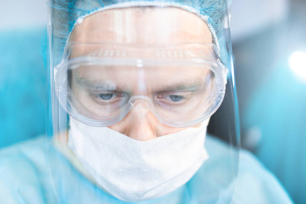 外科医は眼鏡と保護シールドとマスクで。手術室で働く若い専門家 - 写真・画像