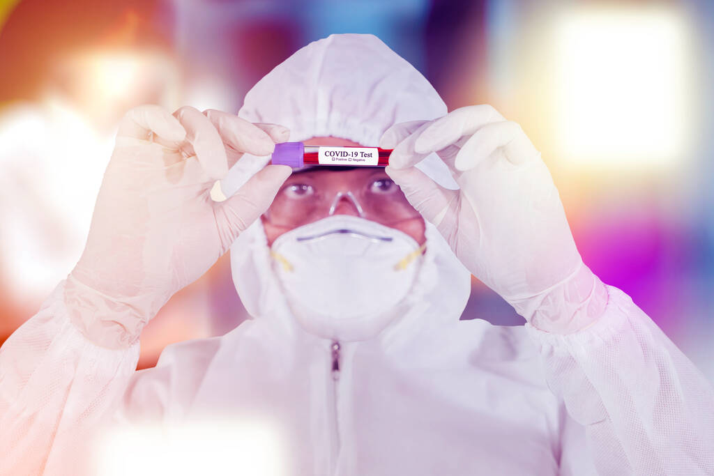 Naukowiec w kombinezonie ochronnym trzymający probówkę z krwią do analizy i pobierania próbek koronawirusu - Zdjęcie, obraz