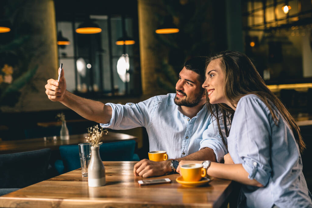 pareja joven tomando fotos con smartphone en el restaurante
 - Foto, imagen
