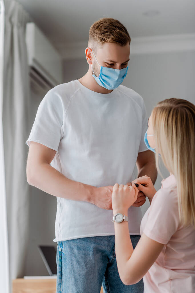 женщина и мужчина в медицинских масках держатся за руки дома
  - Фото, изображение