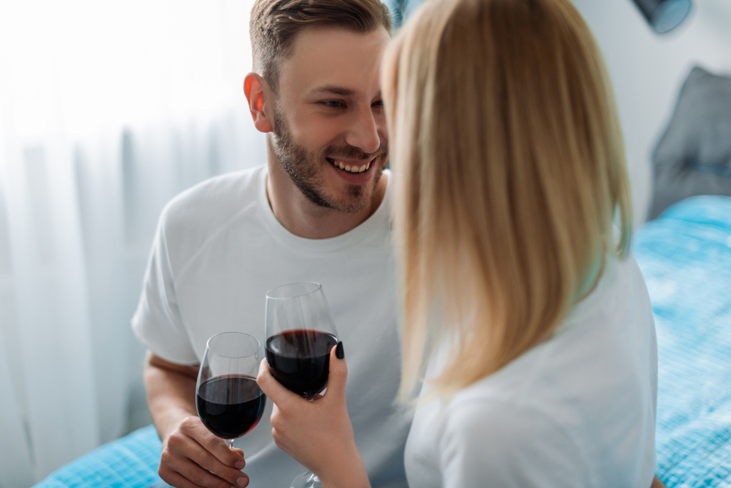 selective focus of happy man and woman holding glasses with red wine  - Photo, Image