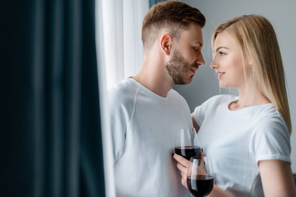 foco seletivo de homem bonito e mulher feliz segurando óculos com vinho tinto
  - Foto, Imagem