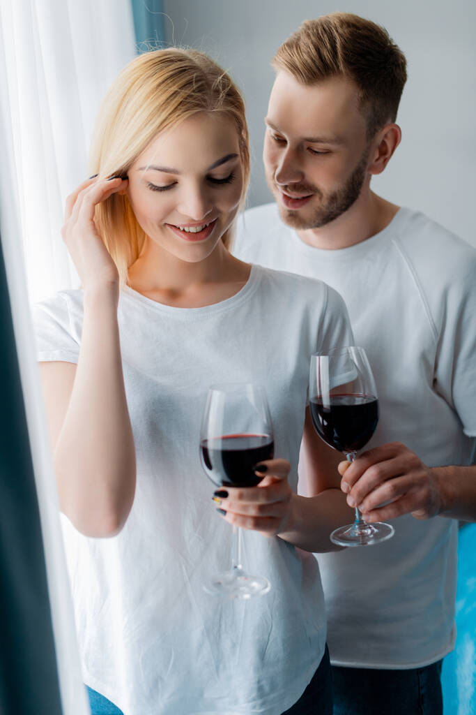 homem bonito olhando para a mulher e segurando vidro com vinho tinto
  - Foto, Imagem