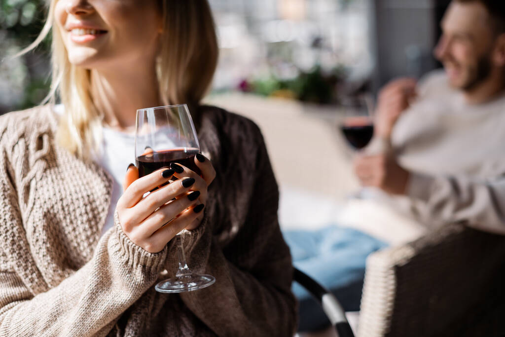 vista ritagliata della ragazza felice che tiene il bicchiere con vino rosso vicino all'uomo
  - Foto, immagini