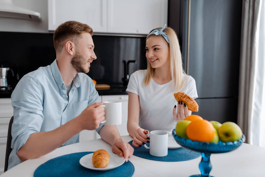 glückliche Frau und Mann schauen einander beim leckeren Frühstück an  - Foto, Bild
