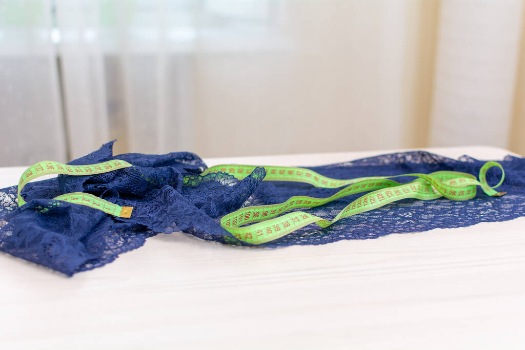 On the table is a blue lace fabric along with a centimeter ribbon. - Photo, Image