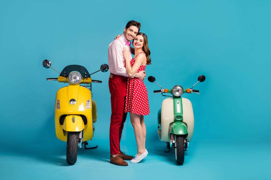 Полная длина фото мечтательный нежные супруги мужчина женщина мотоциклисты имеют свадебное событие поездки езды мотоцикл обнимать обнимать носить красные пунктирные рубашки платье изолированный синий цвет фона
 - Фото, изображение