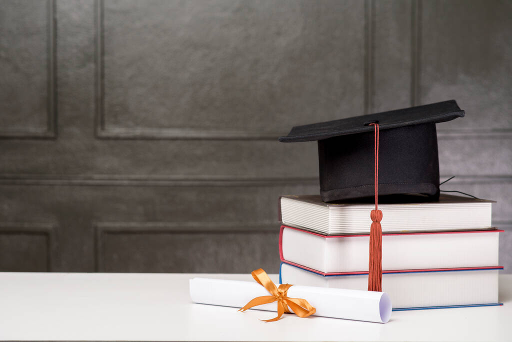 Berretto di laurea con libri su scrivania bianca, sfondo Education
  - Foto, immagini