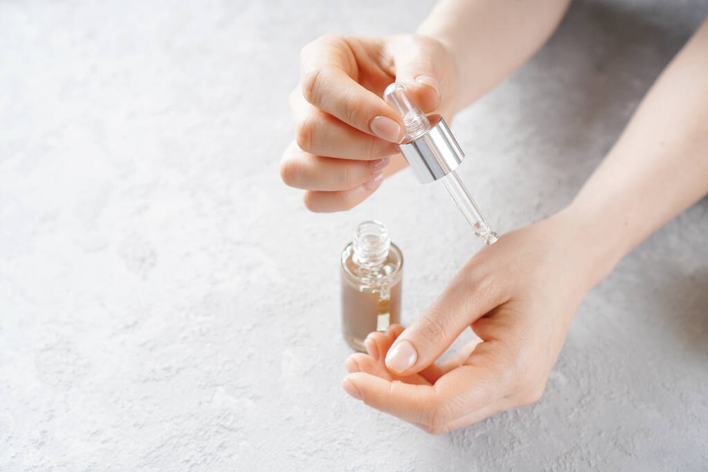 Putting essential aroma oil on female hand  - Photo, Image
