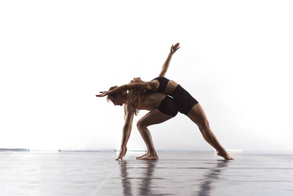fiatal atlétikai táncpartnerek fekete harisnyában modern stílusú balettet játszanak akrobatikus elemek készítése Sportos balett táncosok művészi előadásán fehér háttér előtt - Fotó, kép