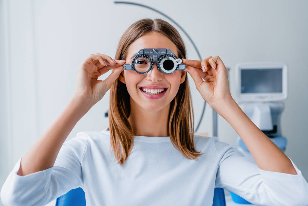Młoda kobieta sprawdzająca wzrok okularami do badań okulistycznych podczas badania lekarskiego w gabinecie okulistycznym - Zdjęcie, obraz