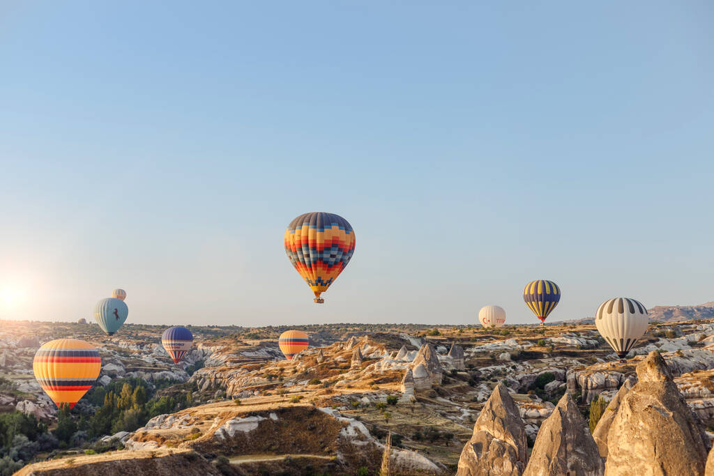 Goreme, Cappadocia, Turecko 23. srpna 2019: Mnoho horkovzdušných balónů na obloze. Lidé se na ně dívají ze země. Zemské pyramidy Cappadocia. Koncept cestovního ruchu. - Fotografie, Obrázek