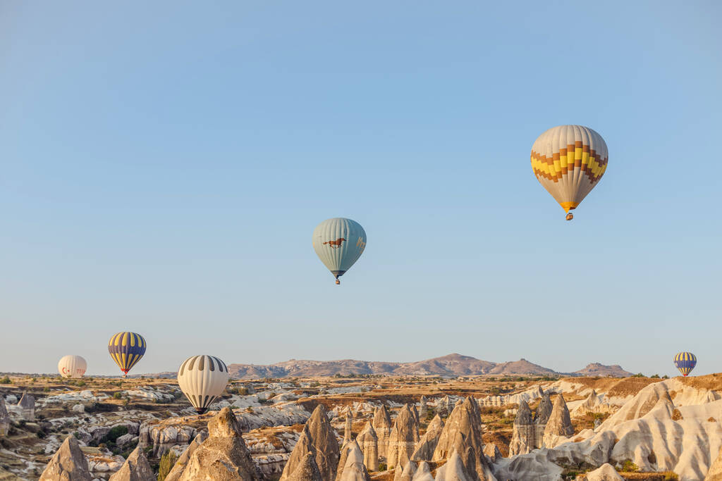 Goreme, Capadocia, Turquía 23 de agosto de 2019: Muchos globos aerostáticos en el cielo. La gente los mira desde el suelo. Capadocia Earth Pyramids. Concepto turístico
. - Foto, Imagen