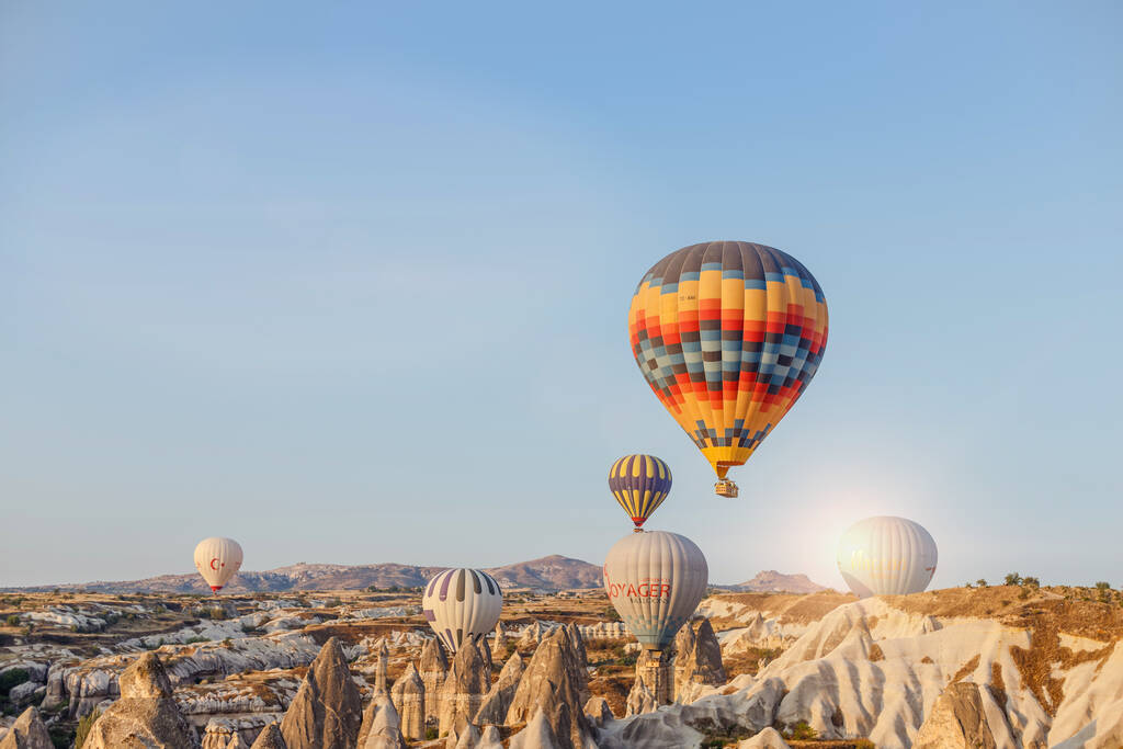 Горме, Каппечия, Турция 23 августа 2019 года: в небе много воздушных шаров. Люди смотрят на них с земли. Земные пирамиды Каппадокии. Концепция туризма
. - Фото, изображение