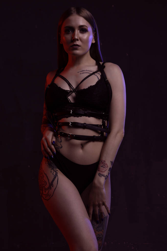 Wunderschöne sexy junge Frau in schwarzer Unterwäsche posiert erotisch auf dunklem Hintergrund - Foto, Bild