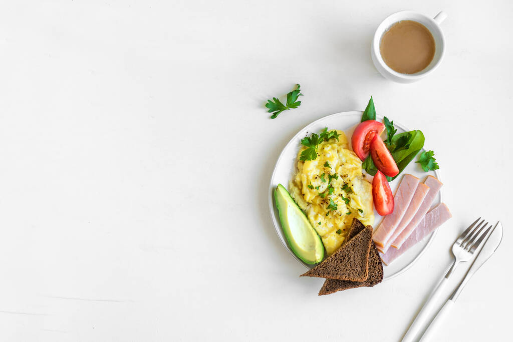Zdrowe śniadanie z jajecznicą, szynką, awokado, pełnoziarnistym tostem żytnim i sałatką, widok z góry, przestrzeń do kopiowania. Keto dieta brunch lub śniadanie. - Zdjęcie, obraz