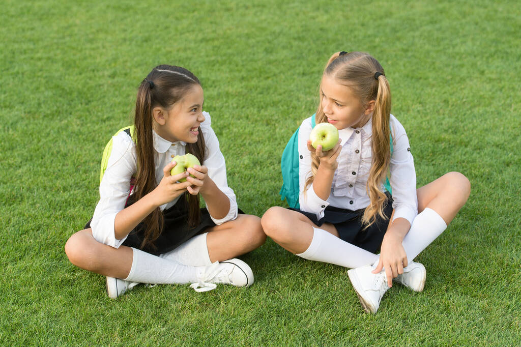 Retour à l'école et saine alimentation. Les enfants heureux mangent des pommes sur l'herbe verte. Une collation scolaire saine. Santé à l'école. Plan de régime pour l'école primaire. Améliorer la santé et l'éducation des enfants - Photo, image