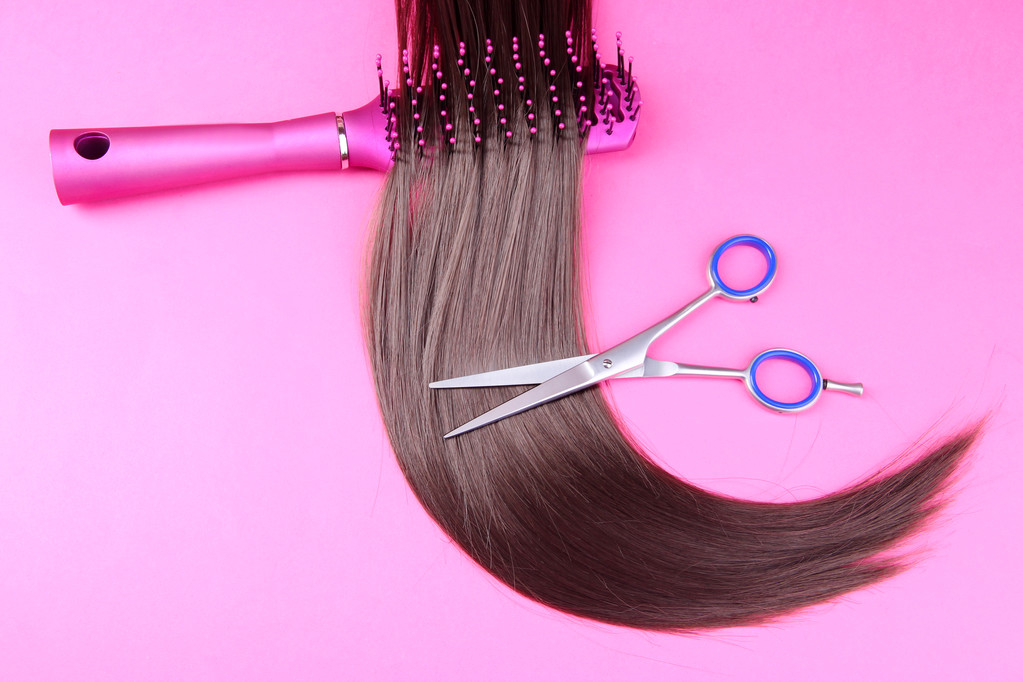 Cheveux longs bruns avec brosse à cheveux et ciseaux sur fond rose
 - Photo, image