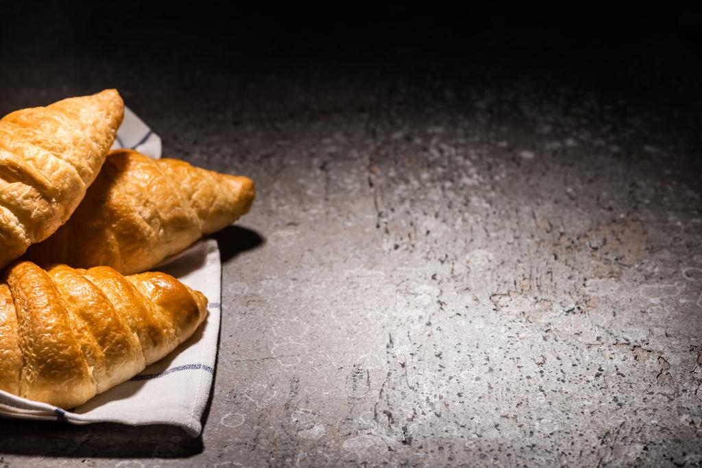 croissants cozidos no forno fresco na toalha na superfície cinzenta concreta no escuro
 - Foto, Imagem