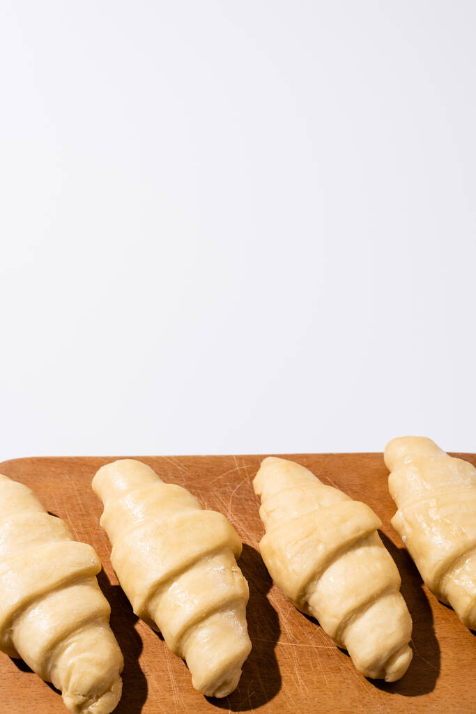 croissant grezzi su tagliere in legno isolato su bianco
 - Foto, immagini