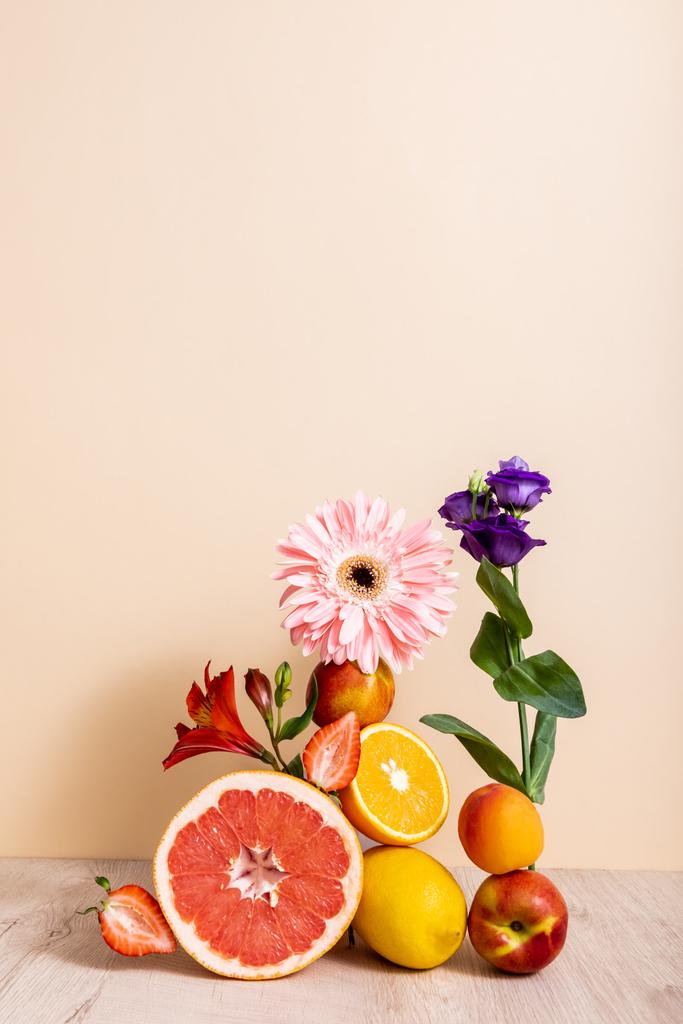 floral and fruit composition with Eustoma, gerbera, Alstroemeria, citrus fruits, strawberries and peaches on beige background - Photo, Image