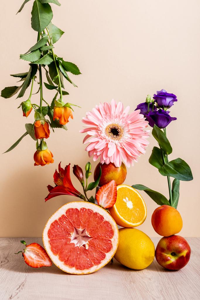 floral and fruit composition with roses, Eustoma, gerbera, Alstroemeria, citrus fruits, strawberries and peaches on beige background - Photo, Image