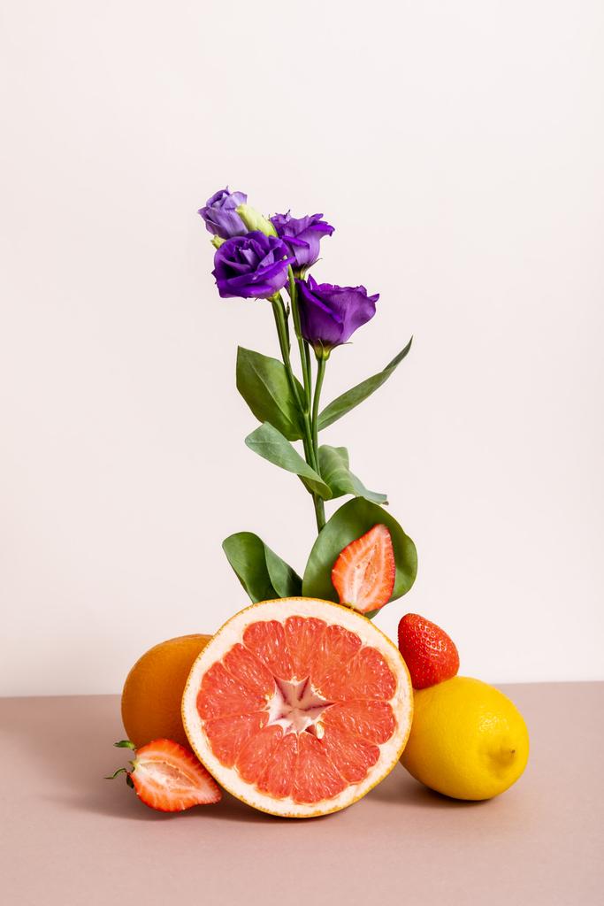 composizione floreale e fruttata con eustoma viola e frutti estivi isolati su beige
 - Foto, immagini