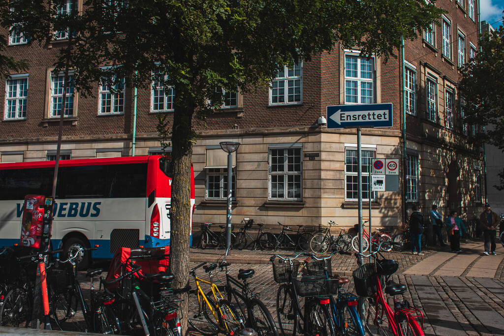 COPENHAGEN, DINAMARCA - 30 DE ABRIL DE 2020: Bicicletas cerca del árbol y fachada del edificio en la calle urbana
  - Foto, imagen
